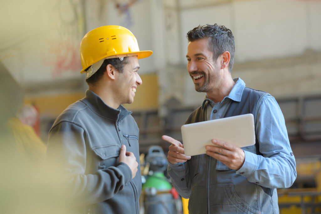 Recruiter talking with a worker in a hard hat at an industrial plant